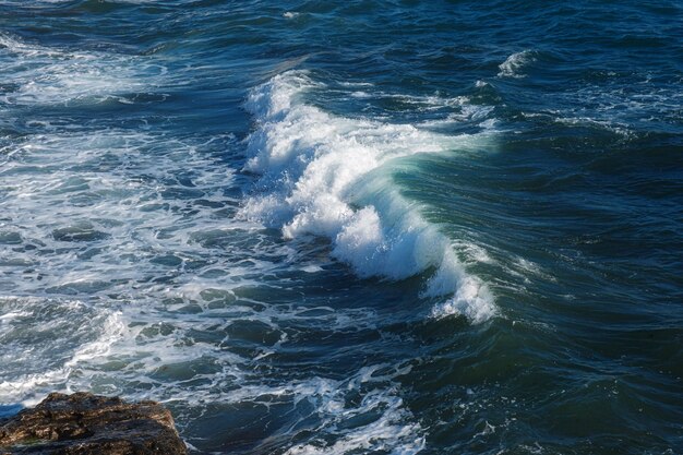 Ozeanwellenhintergrund, der das felsige Ufer des Meerwassers bricht