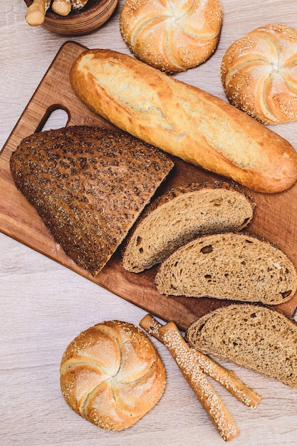 P¡risp Brot mit Brötchen. Französische Baguettes. Frisches Knäckebrot. Brothintergrund. Unterschiedliche Rasse auf hölzernem Hintergrund.