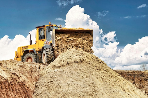 Pá carregadeira de rodas ou escavadeira poderosa trabalhando em uma pedreira ou canteiro de obras Carregadeira com um balde cheio de areia Equipamento moderno e poderoso para terraplenagem