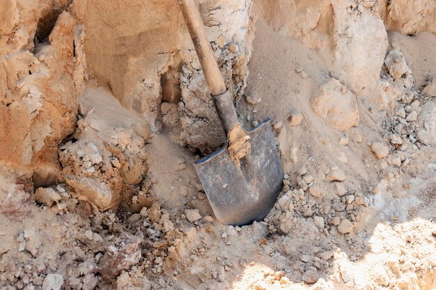 Pá de colher manchada de concreto em uma pilha de areia para fazer concreto