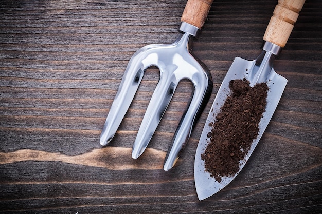 Pá de mão inoxidável com garfo de solo e espátula no conceito de jardinagem de tábua de madeira vintage