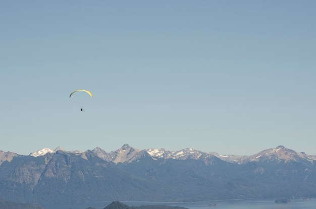 Paaglider fliegt horizontal über die Bergkette mit Kopierraum