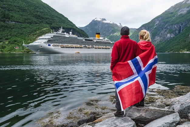 Foto paar am ufer des fjords schaut auf ein kreuzfahrtschiff, norwegen