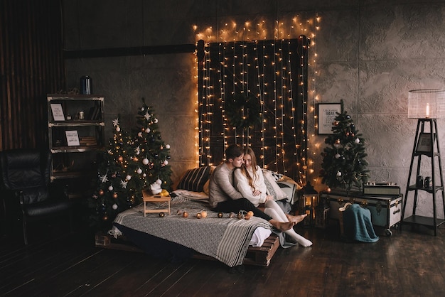 Paar auf dem Bett im Schlafzimmer dunkles Interieur Neujahr und Weihnachten Umarmungen und Küsse lieben weißen Schw...