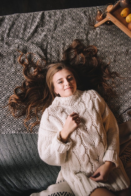 Foto paar auf dem bett im schlafzimmer. dunkles interieur. silvester und weihnachten. umarmungen und küsse. liebe. weißer pullover und hohe socken. romantisches treffen. ein date-liebhaber.