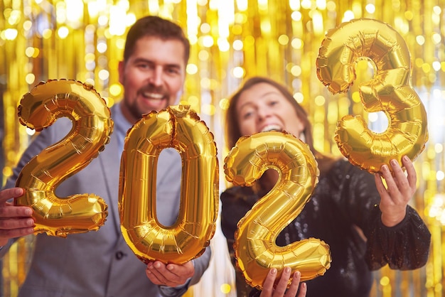 Paar auf der Silvesterparty mit goldenen Luftballons