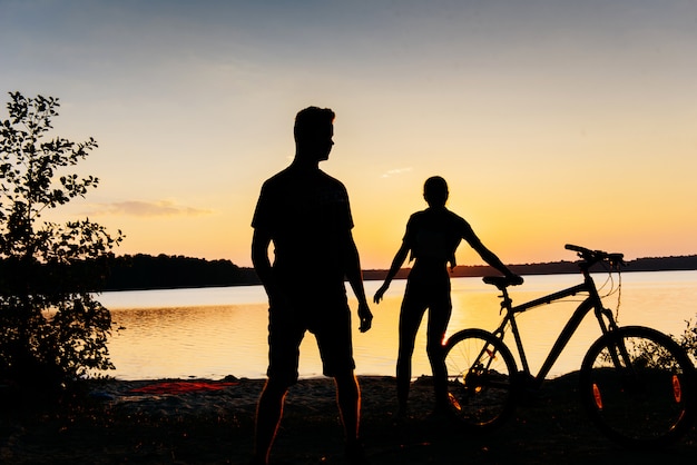 Paar auf einem Fahrrad bei Sonnenuntergang am See