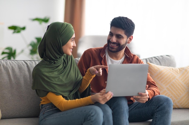 Paar aus dem Nahen Osten mit Laptop-Computer zu Hause sitzen