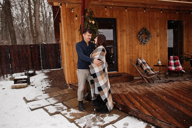 Paar bedeckte Decke am Wintertag, die Zeit miteinander in der Liebe gegen Holzhaus verbringt