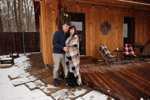 Paar bedeckte Decke am Wintertag, die Zeit miteinander in der Liebe gegen Holzhaus verbringt