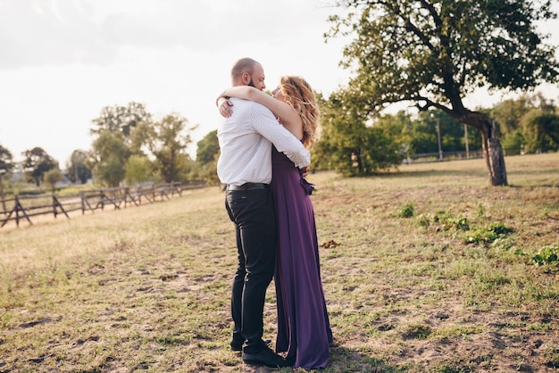 Paar bei einem Date. Lila Kleid. Braut und Bräutigam. Gehen Sie auf dem Feld. Liebesgeschichte.