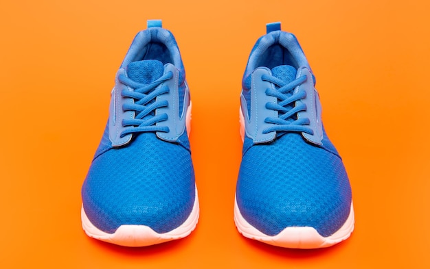 Paar bequeme Sportschuhe sportliche blaue Turnschuhe auf orangefarbenem Hintergrund