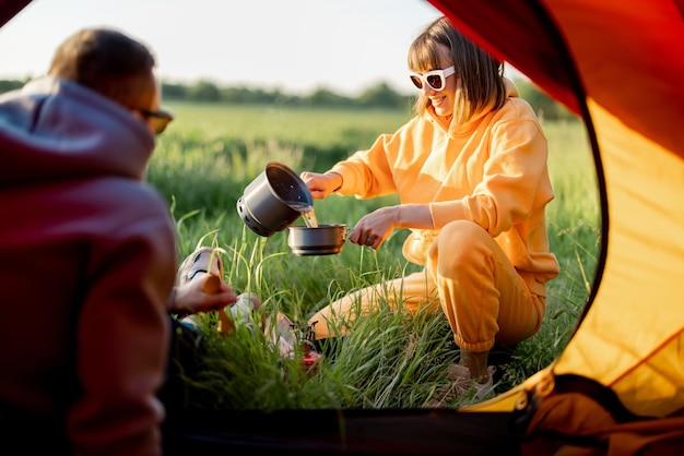 Paar bereitet Essen zu, während es mit Zelt in der Natur unterwegs ist