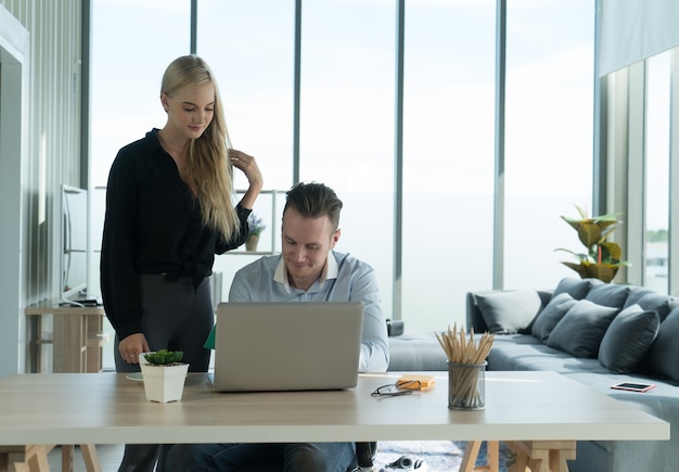 Paar, das an Laptop-Computer mit Entspannung und Glückslächeln arbeitet, arbeitet zu Hause Konzept