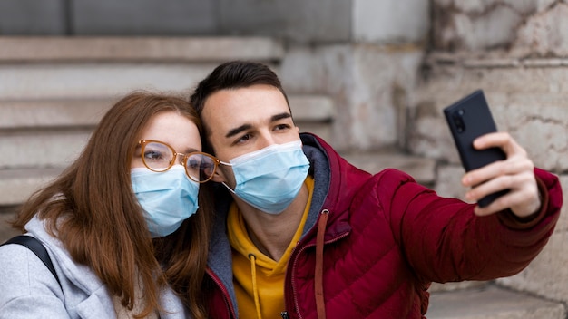 Paar, das ein Selfie zusammen nimmt, während es medizinische Masken trägt