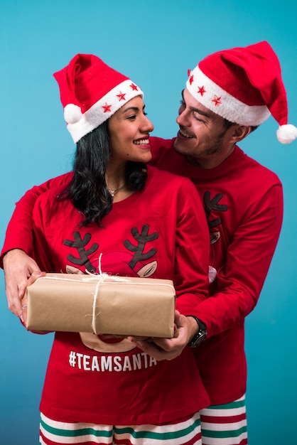 Paar, das ein Weihnachtsgeschenk hält, schauen sich an