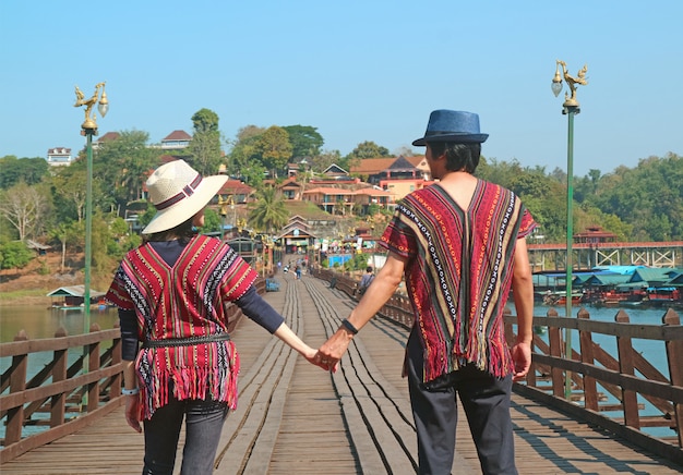 Paar, das Hand in Hand auf Mon Bridge oder Saphan Mon, dem Wahrzeichen von Sangkhlaburi, Thailand, geht