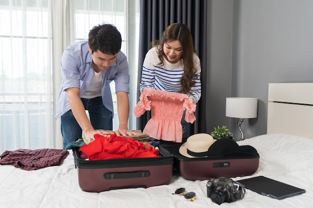 Paar, das kleidung in den koffer auf dem bett zu hause urlaubsreisekonzept vorbereitet und verpackt