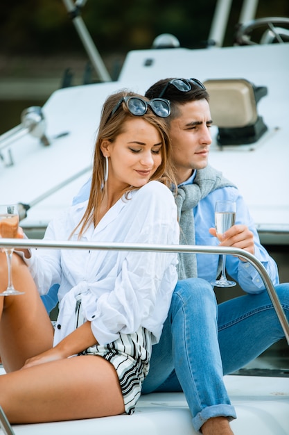 Foto paar, das mit champagner auf einem boot feiert. attraktiver mann, der champagner entkorkt und party mit freundin im urlaub hat. zwei junge touristen, die spaß auf bootstour im sommer haben