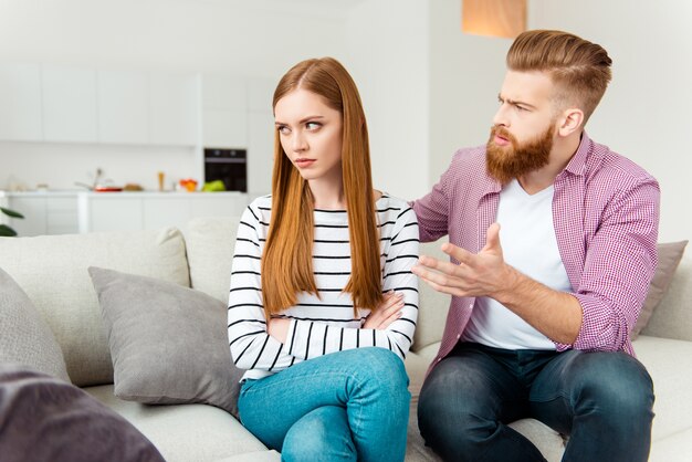 Paar, das zu Hause auf dem Sofa sitzt, verärgert sich gegenseitig