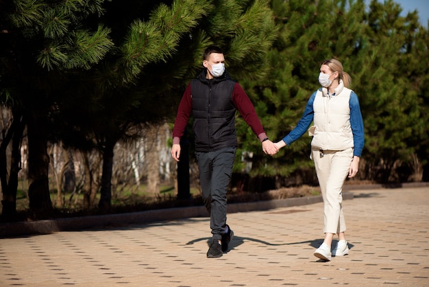 Paar, das zusammen im Park mit medizinischen Masken geht