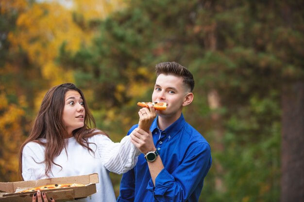 Paar ein Mann und eine Frau jung lustig schön genießen Pizza und Geselligkeit auf einem Picknick in der Natur zusammen