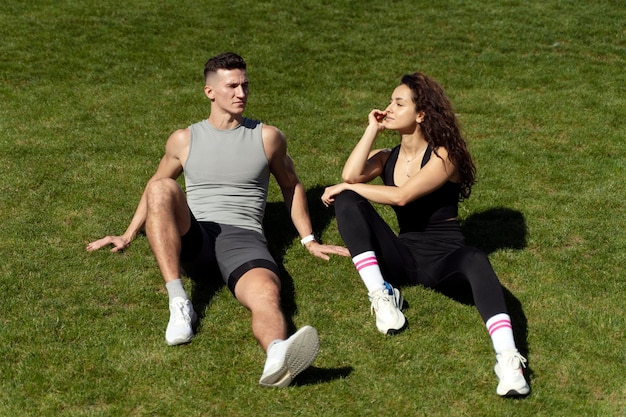 Paar Entspannung im Gras nach dem Training Mann und Frau Erwärmung an der Sonne und lächelnd