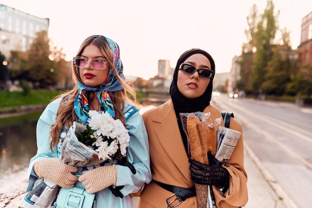 Paar Frau, eine trägt einen Hijab und ein modernes, aber traditionelles Kleid und die andere trägt ein blaues Kleid