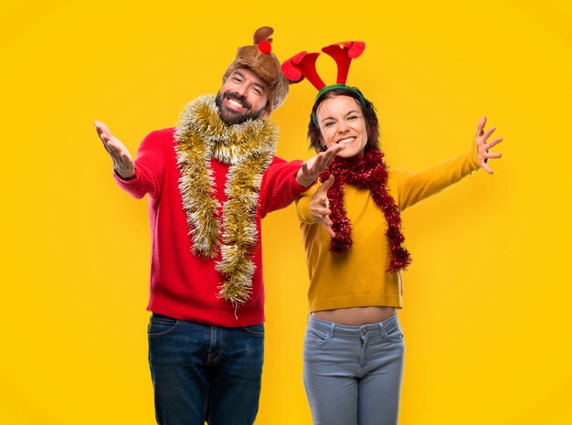 Paar gekleidet für die Weihnachtsfeiertage präsentieren und einladen, zu kommen