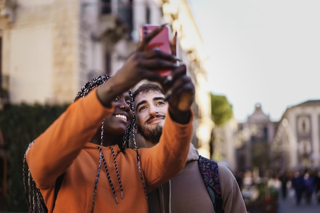 Paar gemischtrassige junge Leute, die eine europäische Stadt besuchen und gemeinsam Selfies machen