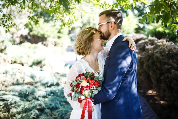 Paar genießt romantische Momente im Park Elegante Braut im schönen weißen Kleid Bräutigam im Anzug