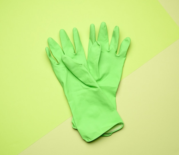 Paar grüne Schutzgummihandschuhe zur Reinigung auf grüner Draufsicht