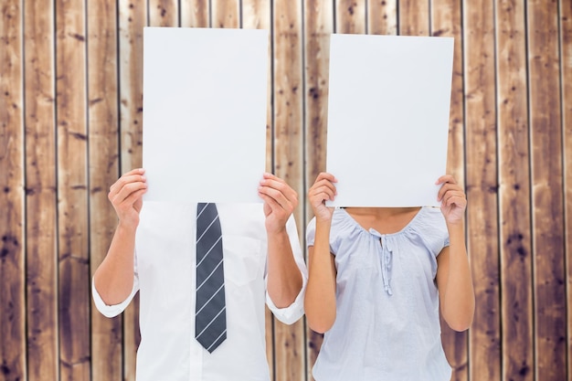 Foto paar hält papier über ihre gesichter vor holzbohlen hintergrund