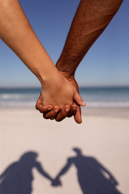 Paar hält sich am Strand im Sonnenlicht an den Händen