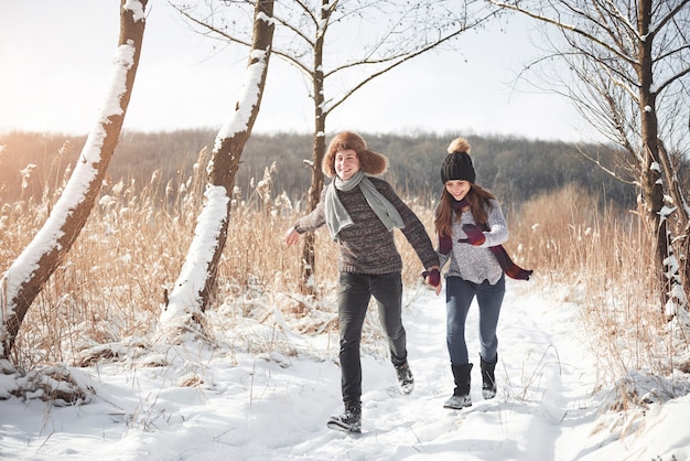 Paar hat spaß und lacht. kuss. junge hippie-paare, die im winterpark sich umarmen. winterliebesgeschichte, ein schönes stilvolles junges paar. wintermode-konzept mit freund und freundin