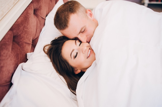 Paar im Bett. glückliches Mädchen und Freund unter der Decke.