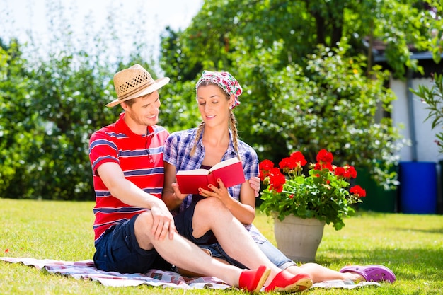 Paar im Garten auf Decke Lesebuch