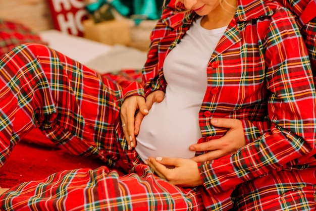 Paar im karierten Pyjama Schwangerer Bauch