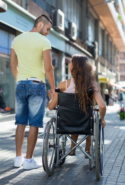 Paar im Rollstuhl zu Fuß durch die Stadt