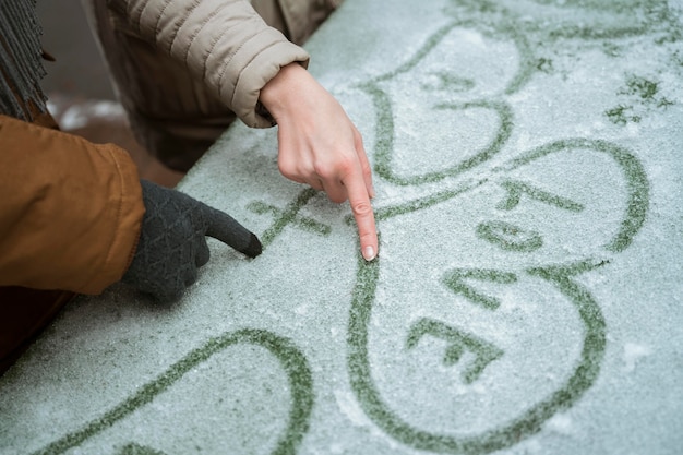 Paar im Winter, das Liebe mit Herz im Schnee schreibt