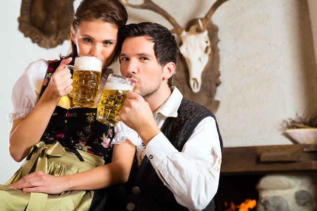 Paar in einer traditionellen Berghütte mit Kamin, die Bier trinkt