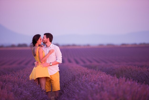 paar in lila lavendelblumenfeld küssen und romantische zeit im sonnenuntergang haben