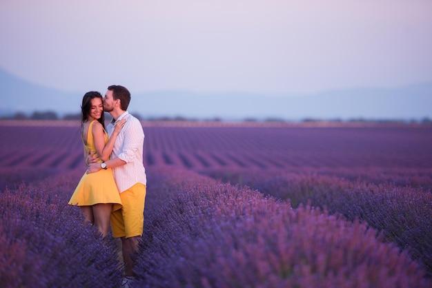 paar in lila lavendelblumenfeld küssen und romantische zeit im sonnenuntergang haben