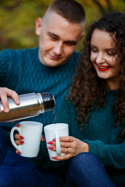 Foto paar in pullovern trinkt tee im herbstwald