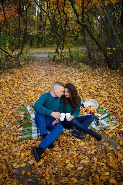 Paar in Pullovern trinkt Tee im Herbstwald