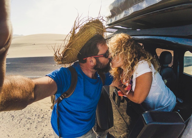 Foto paar küsst sich im auto auf sand in der wüste