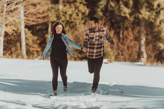 Paar läuft und Händchen haltend im verschneiten Winterwald Selektiver Fokus