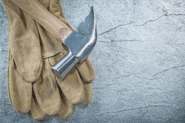 Paar Lederschutzhandschuhe Klauenhammer auf metallischem Hintergrund Konstruktionskonzept.