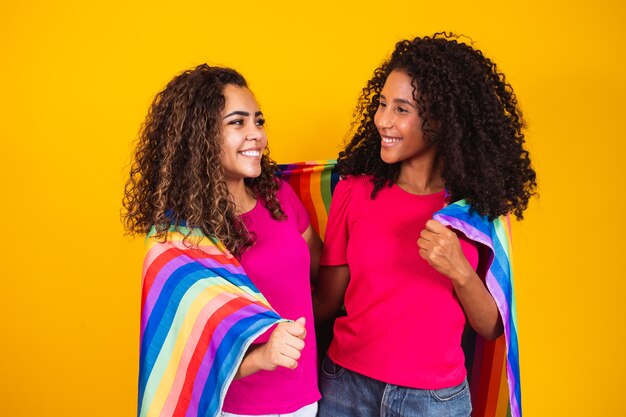 Paar lesbische Frau mit Gay-Pride-Flagge im gelben Hintergrund