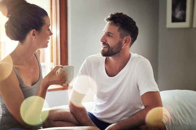 Paar liebe und entspannen im bett mit tee binden und plaudern am wochenende morgen glücklicher mann frau und trinken kaffee zu hause für komfort beziehungsentwicklung oder teilen erinnerungen im gespräch